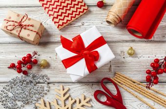 wrapping gift boxes with equipment and decorating items on wooden background