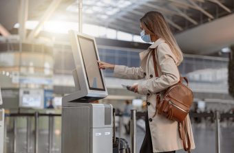 Young woman wearing protective mask and using digital media blank at the airport